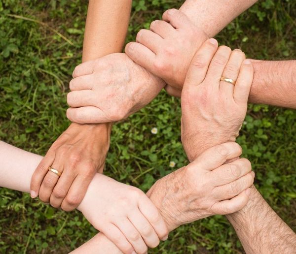 Arms of different people linked together.