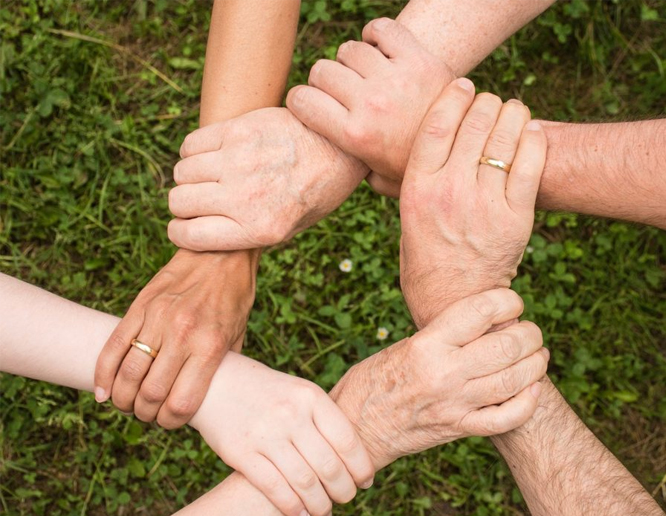 Arms of different people linked together.