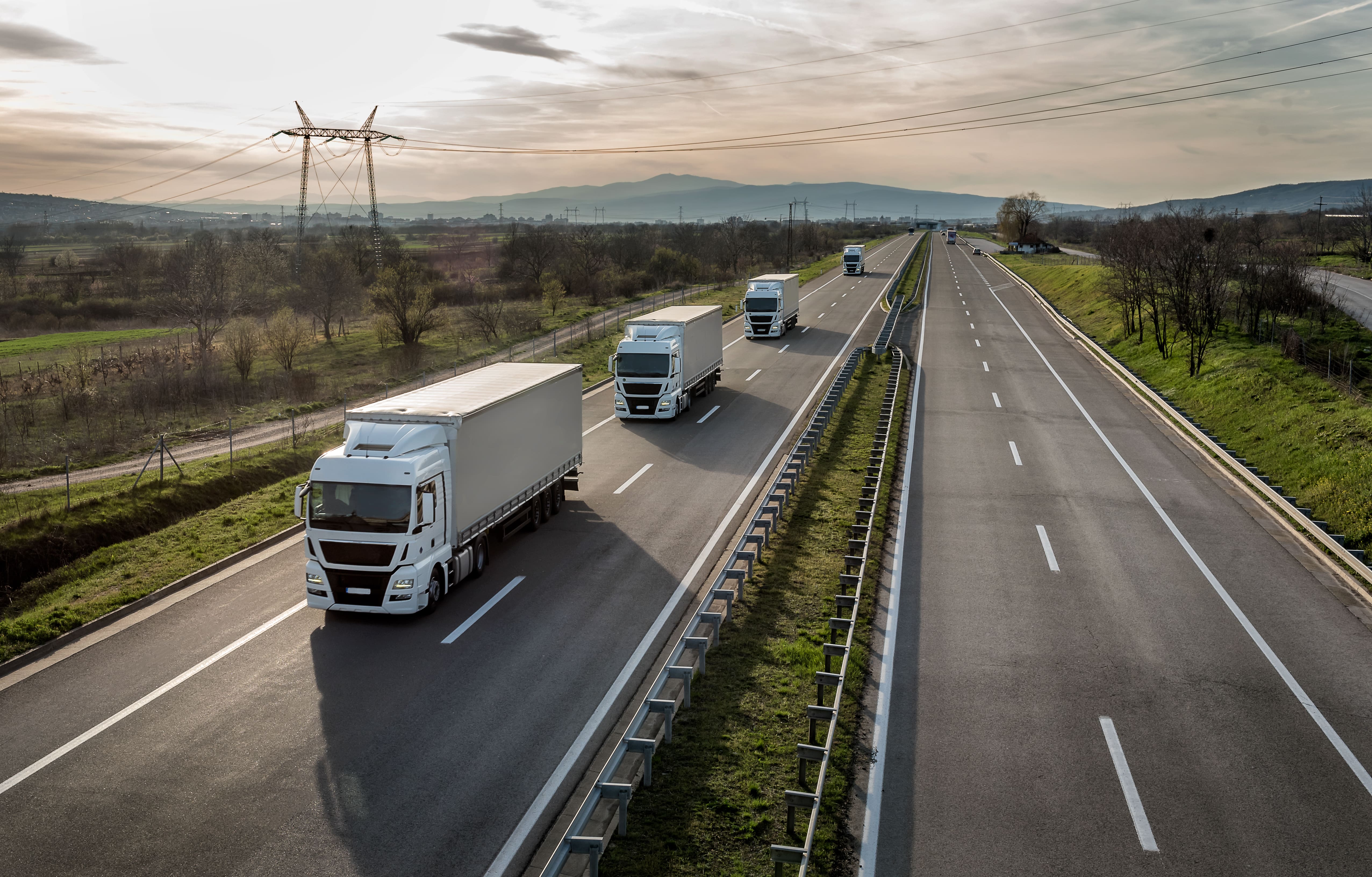 Lorrys driving on a motorway with susnet in the background