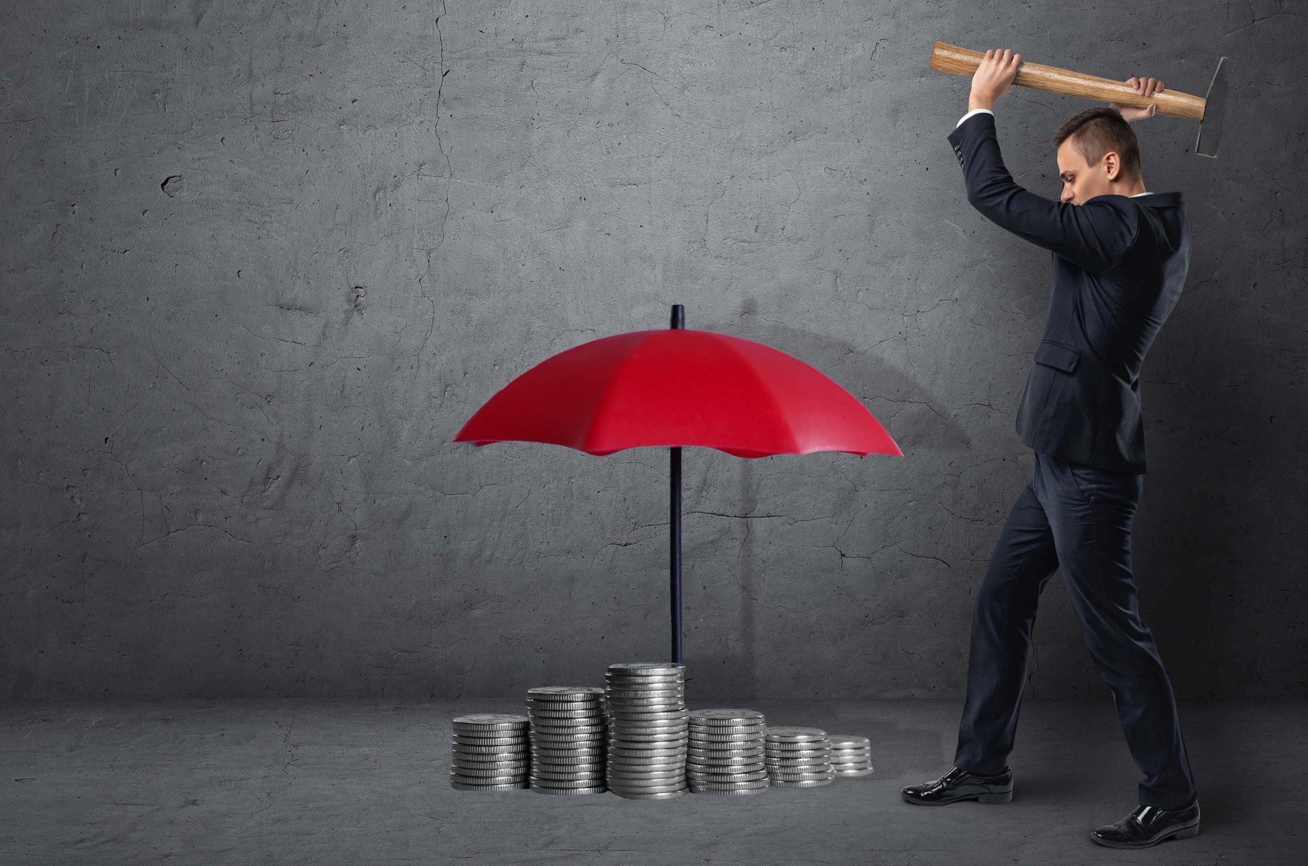 Man Holding hammer about to smash an umbrella with money underneath it.