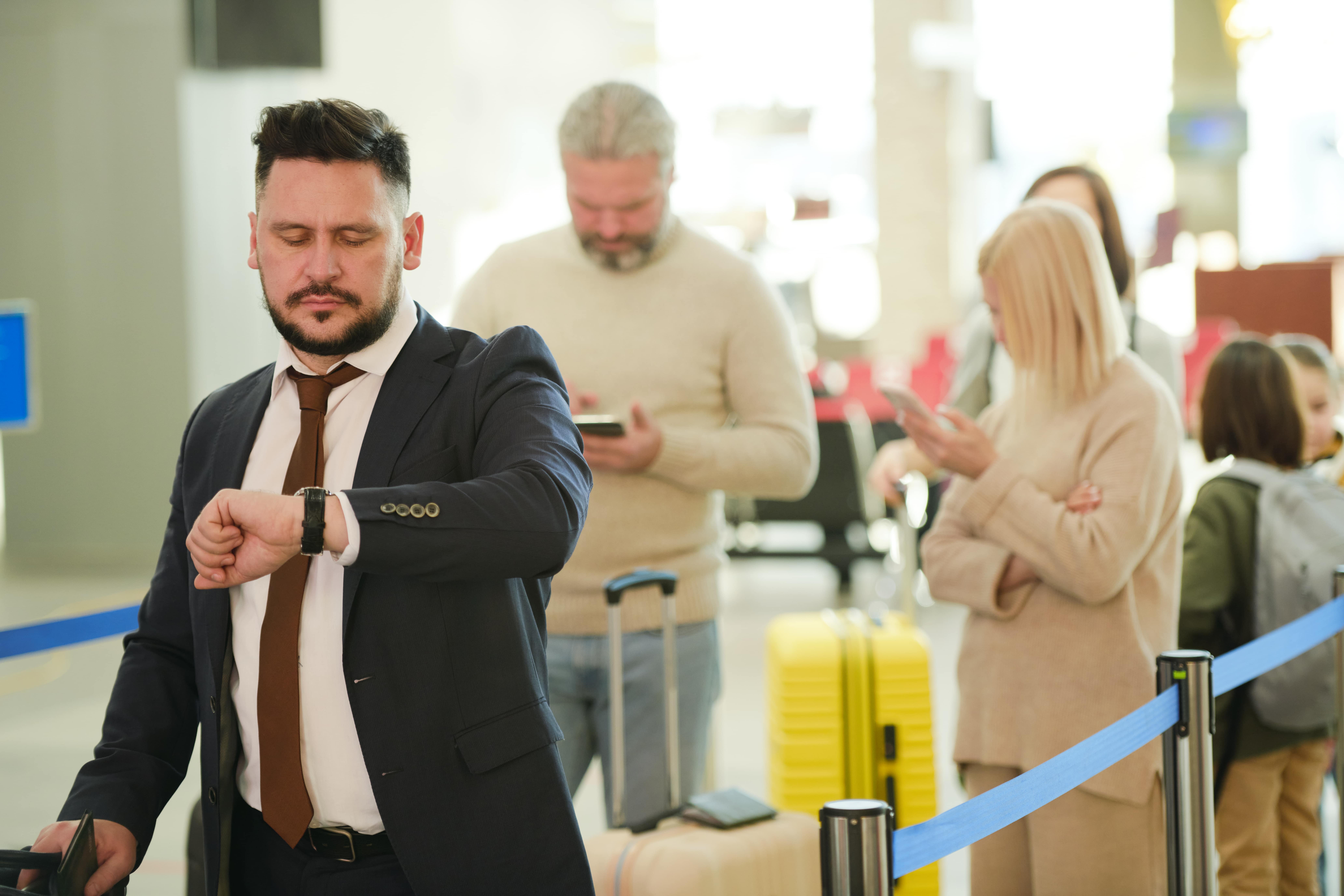 man queueing at the airport, looking at his watch